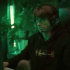 Dendi illuminated by a green light while playing Dota 2.