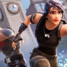 Fortnite battle scene: fierce female agent with dual pistols charging forward, blonde male fighter beside her, clock tower and chaotic city background
